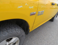 A close-up of a yellow 2015 RAM 1500 truck showing the HEMI logo and part of the tire with visible treads