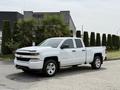 A 2018 Chevrolet Silverado 1500 in white with four doors and chrome accents parked on a driveway