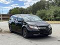 A black 2014 Honda Odyssey parked at an angle with stylish alloy wheels and a sleek design, featuring a prominent front grille and headlights