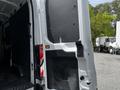 A white 2022 Ford Transit van with its rear doors open revealing a spacious cargo area