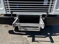 A silver metal loading platform is attached to the front of a 2019 Freightliner MT45 with bolts and a spring mechanism