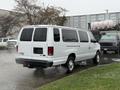 A 2013 Ford E-350 van in white with a sliding side door parked with steam rising from the ground behind it