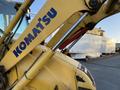 A yellow 2007 Komatsu WB156PS-5 backhoe with a visible logo on the arm is positioned in the foreground