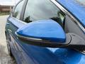 A close-up of the side mirror of a blue 2021 Kia Forte showcasing its sleek design and integrated turn signal indicator