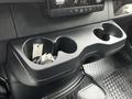 A close-up of the center console of a 2020 Mercedes-Benz Sprinter featuring cup holders and a storage area with keys inside