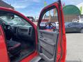A red 2012 RAM 2500 pickup truck with the driver's side door open displaying the interior features and seating