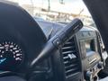 Close-up of the gear shift lever in a 2015 Ford F-150 featuring buttons for towing and sport mode. The dashboard includes gauges and a digital speedometer.