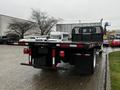 A 2011 International DuraStar 4300 flatbed truck viewed from the rear showing a black bed with red and white reflective striping