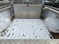 The image shows the bed of a 2010 Ford F-250 SD truck with a diamond plate toolbox in the center and dirt scattered on the white surface