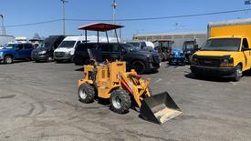 A 2024 Traner TR45 wheeled loader with a yellow body and black bucket positioned in a parking area surrounded by various vehicles