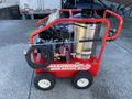 A 2024 Magnum 4000 Hot Water Pressure Washer in red with a large stainless steel tank and a sturdy frame featuring wheels and hoses attached