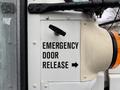 Close-up of a white panel labeled "EMERGENCY DOOR RELEASE" with a lever next to it and an orange light visible