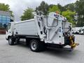A 2014 Hino 195 truck with a white body and a rear loading mechanism is parked with its back end visible showcasing the collection compartment and hydraulic features