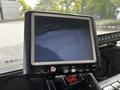 A monitor displaying a video feed, showing a view of the road or ground in front of the vehicle, with red control buttons below it