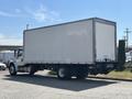 A 2015 Freightliner M2 106 truck with a large white cargo box and a dark chassis is parked with its rear facing the viewer