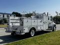A 2004 Freightliner M2 truck with a silver exterior featuring a utility bed and multiple tool compartments mounted on the sides