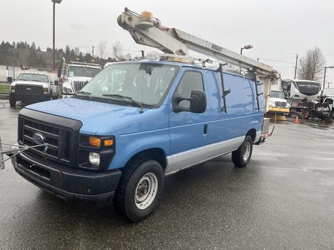 A blue 2009 Ford Econoline van with a utility ladder mounted on the roof and equipment on the front attached to the hitch