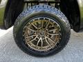 A close-up of a bronze alloy wheel with a rugged tire mounted on a 2019 RAM 1500 showcasing detailed spoke design and a center logo