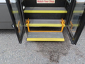 A 2020 Chevrolet Express with open doors revealing yellow steps and a warning sign indicating to watch your step