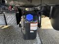 A black DEF tank with a blue cap attached to the side of a 2014 Hino 195 truck