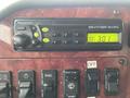 A Panasonic weather band radio display with buttons on a dark wood panel inside a 2003 International 5600i truck cabin showing the time 3:01