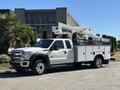 A 2016 Ford F-550 equipped with a utility truck bed and an aerial lift system mounted on the back