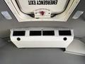 View of an overhead air conditioning unit inside a vehicle with multiple air vents and a sign indicating an emergency exit