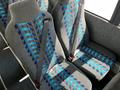 Interior seats of a 2022 Blue Bird BB Conventional bus featuring gray upholstery with blue and turquoise patterned fabric and seat belts attached