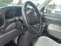 Interior view of a 2004 Ford Econoline with a steering wheel dashboard and front seat in grey upholstery