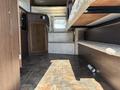 Interior of a 2018 Westland Travelaire showing steps leading to a raised sleeping area and a compact kitchen area with storage cabinets