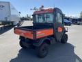 A 2018 Kubota ATV with an orange and black exterior featuring a maintenance lube sign on the back and a covered cab designed for utility and off-road use