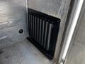 A black metal rack with multiple cylindrical holders mounted on a silver surface inside a vehicle