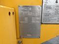 A metal information plate attached to a yellow surface featuring technical specifications and details for a 2015 Freightliner M2 106 truck