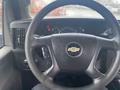 Steering wheel and dashboard of a 2018 Chevrolet Express with a Chevy logo and various dials and controls visible behind the wheel