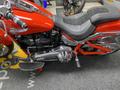 A 2024 Harley Davidson Fat Boy motorcycle in vibrant red with black leather seating and chrome details showcasing its powerful engine and sleek design