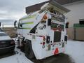 2015 Global Street Sweeper with a white and green design featuring a distinct rear hopper and various lights and reflectors on the back
