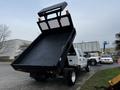 A 2015 Ford F-550 truck with a black dump bed elevated at the rear