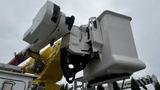 A 2006 International 7500 bucket truck with a raised articulating boom and a spacious white bucket for carrying personnel and equipment