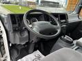 Interior view of a 2018 Isuzu NRR truck with a steering wheel dashboard and gear shift, featuring various controls and gauges