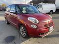 A red 2015 Fiat 500L with a rounded front design and chrome accents is parked, showcasing its compact size and distinctive style