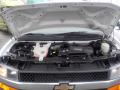 A 2011 Chevrolet Express with the hood open displaying its engine compartment featuring various mechanical components and fluids