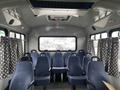 Interior of a 2012 Chevrolet Express with blue seats arranged in rows and patterned curtains on the windows