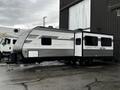 A 2022 Aspen Trail travel trailer with a sleek gray exterior and bold white lettering featuring the brand name and mountain graphic