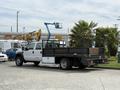 A white 2008 Ford F-550 flatbed truck with a black bed parking in a lot