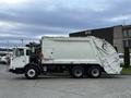 A white 2010 Autocar Xpeditor garbage truck with a large rear compactor and a side-loading mechanism