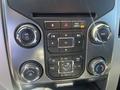 Dashboard control panel of a 2014 Ford F-150 featuring buttons for volume air conditioning and audio functions