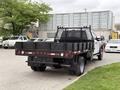 A 2020 Ford F-550 truck with a flatbed and a black mesh safety guard at the rear facing slightly to the right