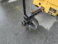 A close-up view of a 2014 Vermeer Corporation Sweep Stump Cutter featuring a black and yellow frame with a wheel and a support arm visible in the foreground