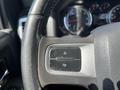 Close-up of the steering wheel controls in a 2011 RAM 1500 featuring two buttons with up and down arrows for adjusting settings