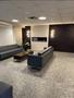 A modern lounge area with two sleek sofas and a coffee table in front of a wall-mounted electric fireplace